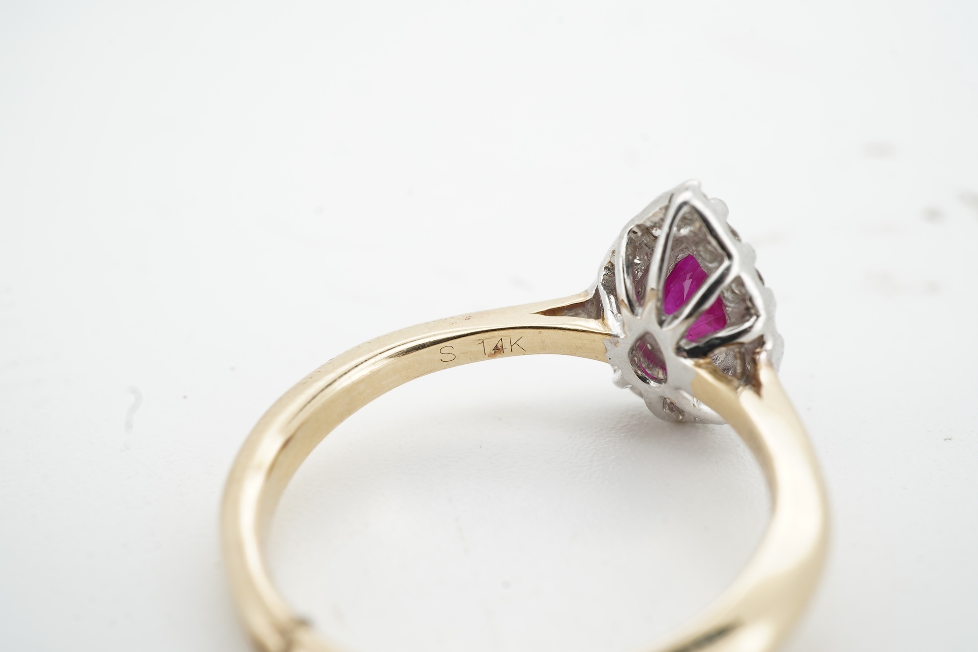 A ruby and diamond cluster ring, claw-set with a pear-shaped ruby weighing approximately 0.60 carats, within a border of brilliant-cut diamonds totalling approximately 0.42 carats, mounted in 14ct gold, size N, British h